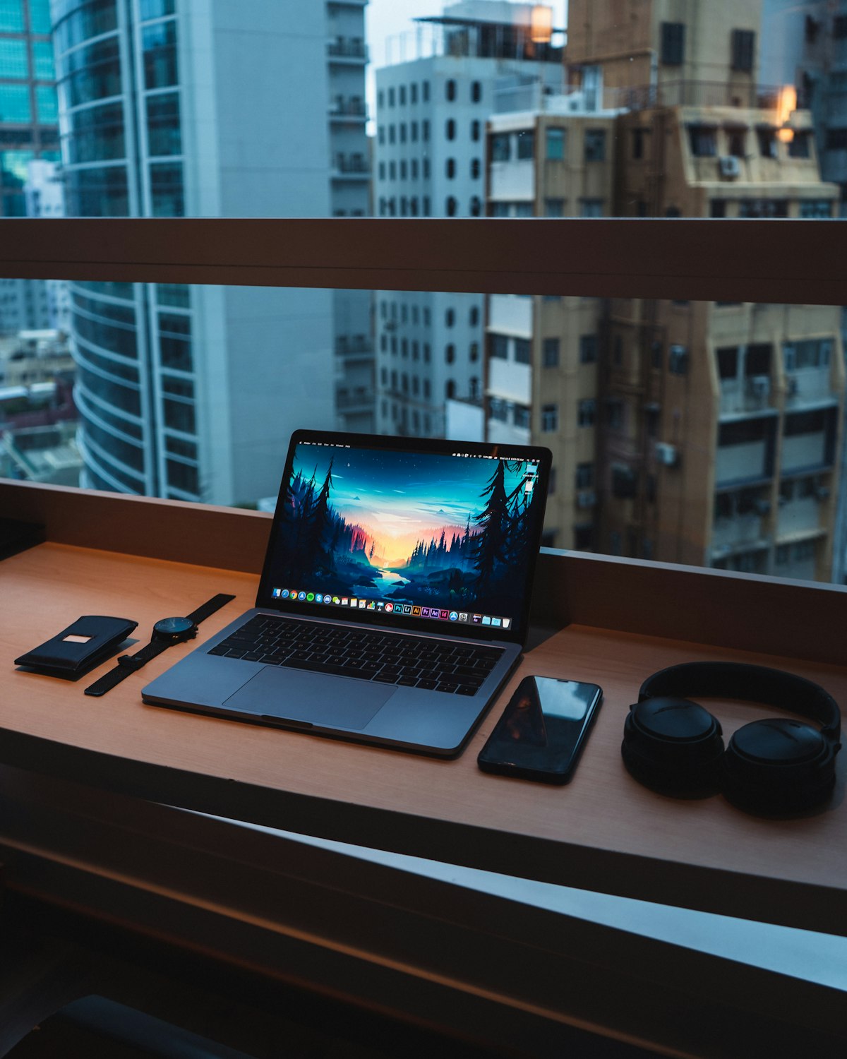 Laptop on a desk beside a window with a city view
